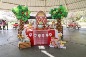 A table with balloons and decorations in the shape of a barn.