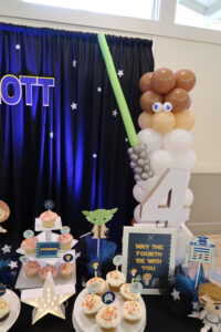 A table with balloons and decorations for a star wars party.