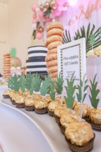 A table with cupcakes and pineapple decorations on it.