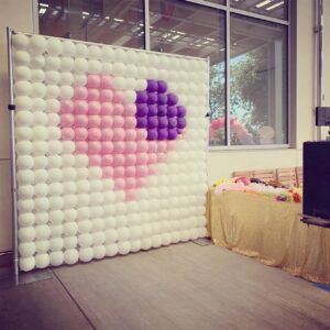 A photo of a balloon wall with a heart on it.