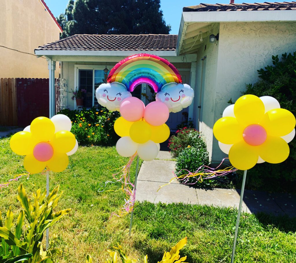 A rainbow balloon is in the shape of a flower.