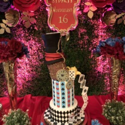 A tall cake with a top hat and clock on it.