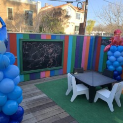 A table and chairs with balloons on the ground