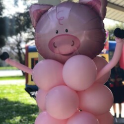 A pig balloon sculpture is in the grass.