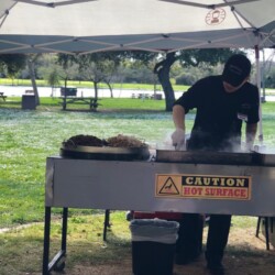 A man cooking food on top of an outdoor grill.
