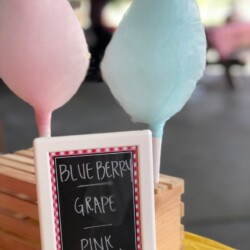 A chalkboard sign with two cotton candy sticks.