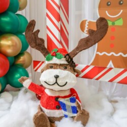 A stuffed animal dressed as rudolph sitting in the snow.