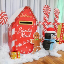 A red mailbox with santa claus and penguins on it.