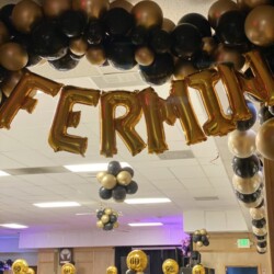 A room filled with balloons and gold foil letters.