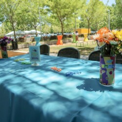 A table with blue cloth and flowers in vases.
