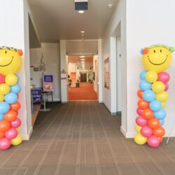 A hallway with two columns of balloons and one is smiling.