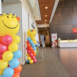 A room with many balloons and a large smile face.