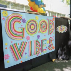 A sign that says good vibes with balloons in the background.