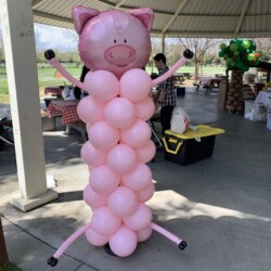 A pig balloon sculpture is in the shape of a person.