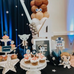 A table with star wars themed desserts and balloons.