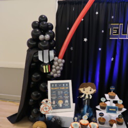 A table with balloons and decorations for a star wars party.