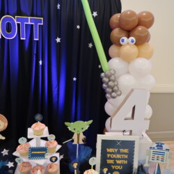 A table with balloons and decorations for a star wars party.