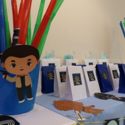 A table with several bags of candy and a boy.