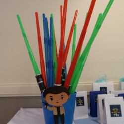 A blue cup with red, green and blue straws in it.
