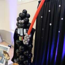 A tall black balloon tower with balloons attached to it.