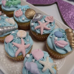 A plate of cupcakes with sea shells and starfish.