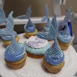 A white plate topped with cupcakes covered in blue frosting.