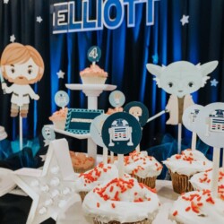 A table with star wars themed cupcakes and decorations.
