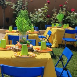 A table set up with blue chairs and yellow tablecloth.