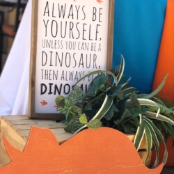 A sign that says " always be yourself, unless you can be a dinosaur then always be a dinosaur ".
