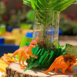 A table with some green plants and plastic dinosaurs