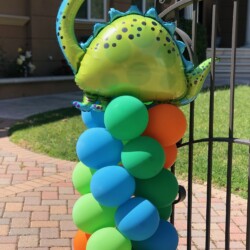 A balloon sculpture of an octopus on the side of a fence.