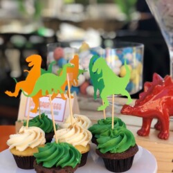 A plate of cupcakes with dinosaur decorations on them.
