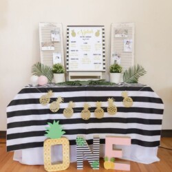A table with a black and white striped cloth, pineapple decorations, and letters.