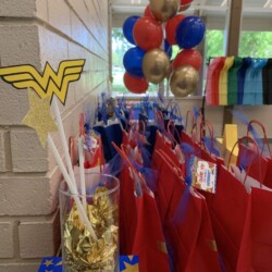 A table with red bags and gold balloons.