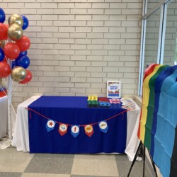 A table with balloons and a sign that says " proud ".