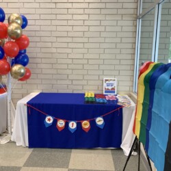 A table with balloons and a sign that says " proud ".