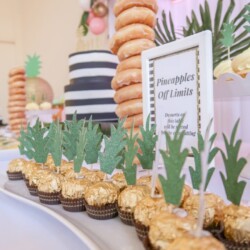 A table with cupcakes and pineapple decorations on it.