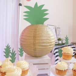 A pineapple decoration and cupcakes on the table.