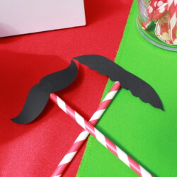 A pair of paper mustaches on top of two straws.