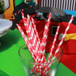 A glass of straws with paper mustache and lips.