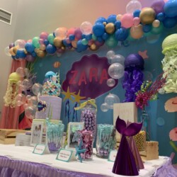 A table with balloons and other decorations on it.