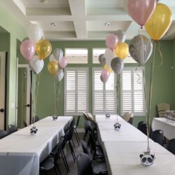 A room with tables and chairs, balloons in the air.