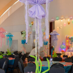 A room filled with tables and chairs decorated in purple.