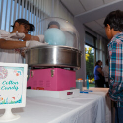 A table with people standing around it and some food