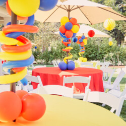 A table with balloons and chairs in the background.