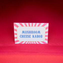 A red table with a sign that says mushroom cheese kabob.