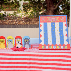 A table with a red and white striped cloth, four wooden animals on it.