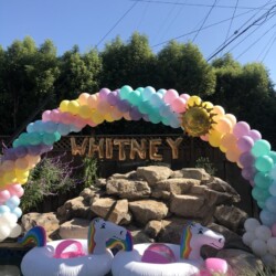 A balloon arch with balloons and unicorn floats.