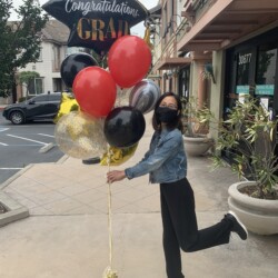 A woman is running with balloons on the street.