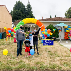 A family posing for a picture in front of balloons.